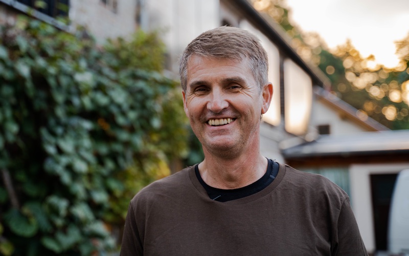 Jörrg Gauger lächelnd vor der Bäckerei Röhrig mit Solarpaneelen am Gebäude