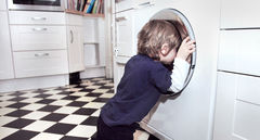 Kind schaut in Waschmaschine, symbolisiert Suche nach energieeffizienten Haushaltsgeräten