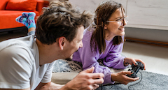 Frau mit Spiele-Controller und Mann schaut zu zum Thema Multimedia