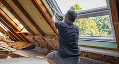 Handwerker, der ein neues Fenster auf dem Dachboden abfässt.