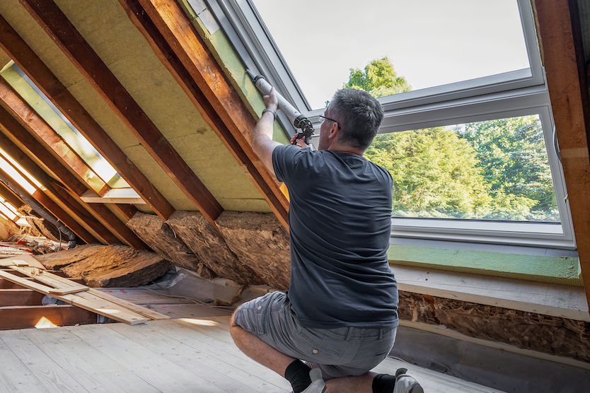 Handwerker, der ein neues Fenster auf dem Dachboden abfässt.