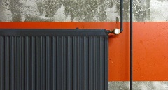 Symbolbild für Energieeffizienz in öffentlichen Gebäuden: schwarze Heizung vor Wand