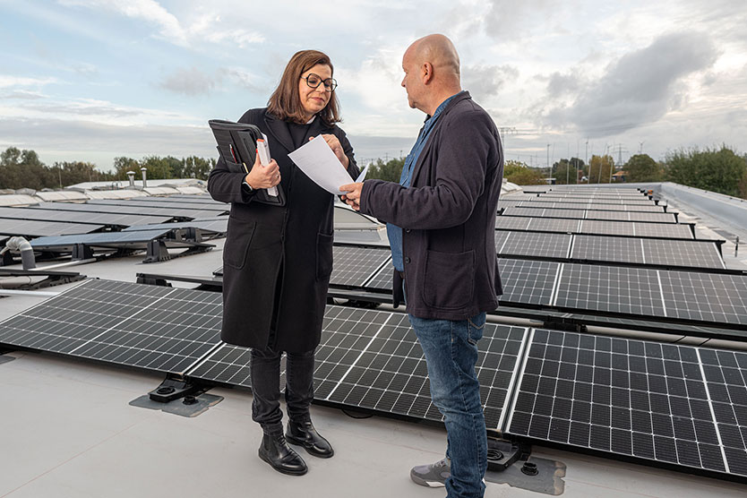Zwei Personen in Gespärch auf Hausdach mi Solaranlage als Symbol für Energieberatung für Privatpersonen, Unternehmen und Kommunen