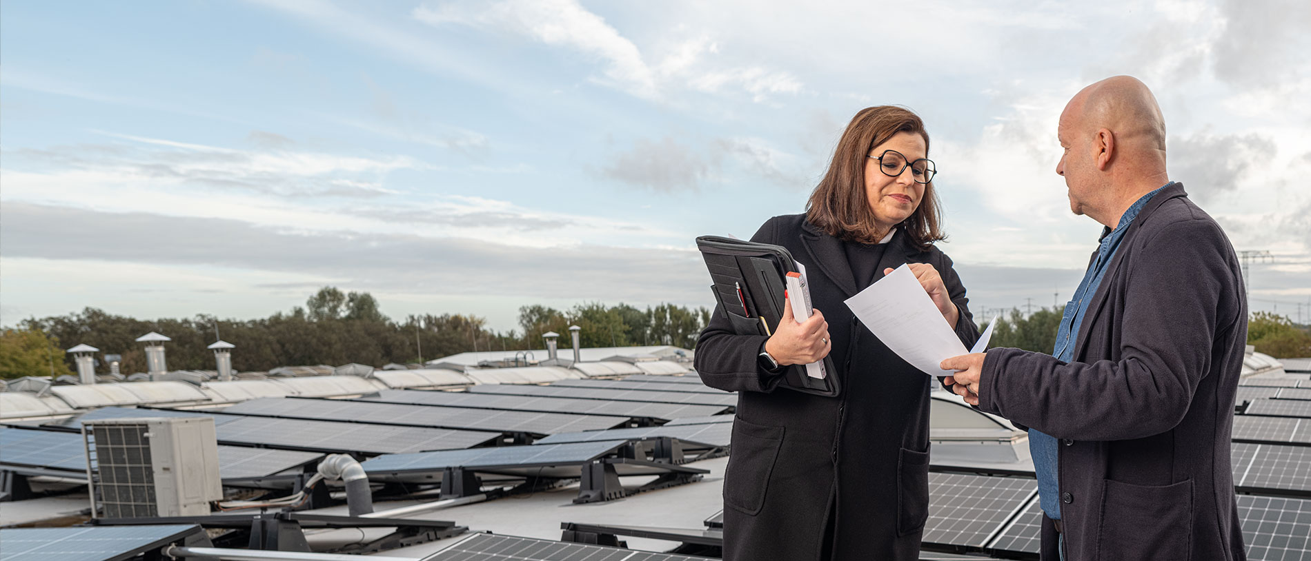 Zwei Personen in Gespärch auf Hausdach mi Solaranlage als Symbol für Energieberatung für Privatpersonen, Unternehmen und Kommunen