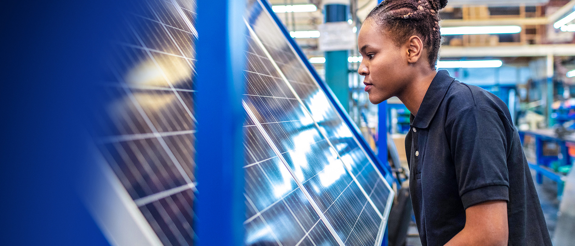Frau in Solarfabrik vor einem Solarpanel