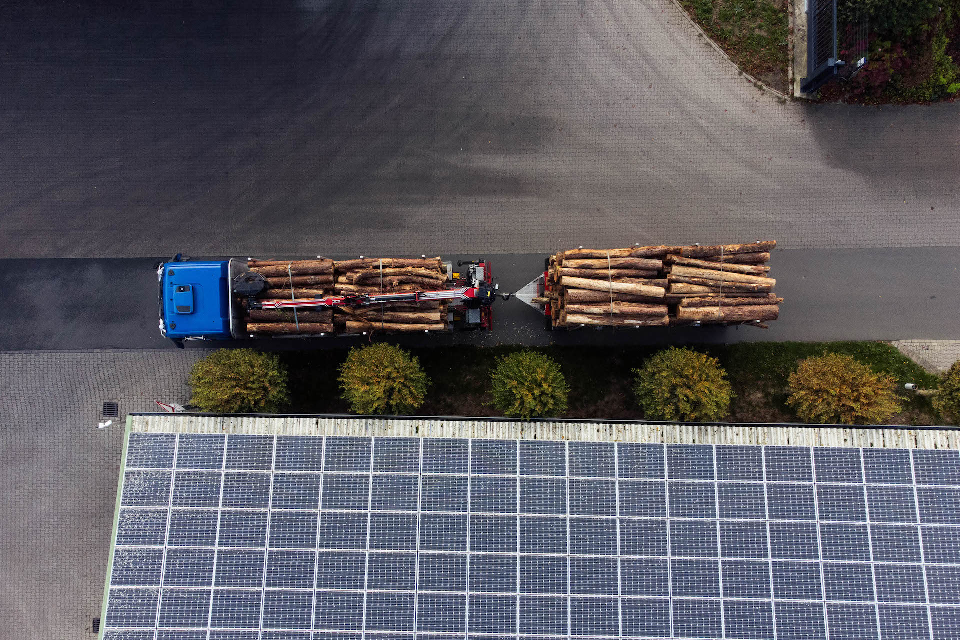 Blick von oben auf Truck mit Holzstämmen und Dach mit Solaranlage